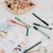 A colorful child's drawing of a family alongside pizza and pens on a table.